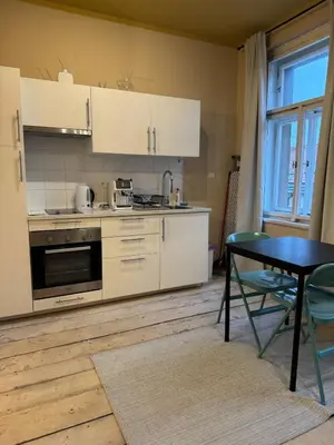 a kitchen with white cabinets and a table and a dining room at Small studio in hipster neighborhood in Prague