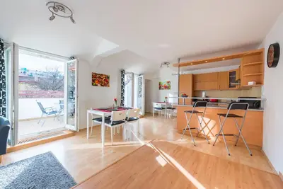 a kitchen and living room with a table and chairs at Duplex City-Centre Apartment with a Sunny Terrace in Prague