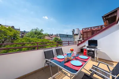 a balcony with a table and chairs on a balcony at Duplex City-Centre Apartment with a Sunny Terrace in Prague