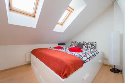 a white bedroom with a bed with a red blanket at Duplex City-Centre Apartment with a Sunny Terrace in Prague