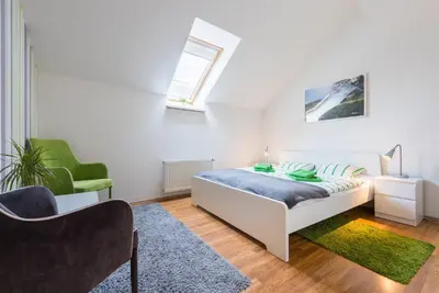 a white bedroom with a bed and a chair at Large Duplex Apartment with a Sunny Terrace in Prague