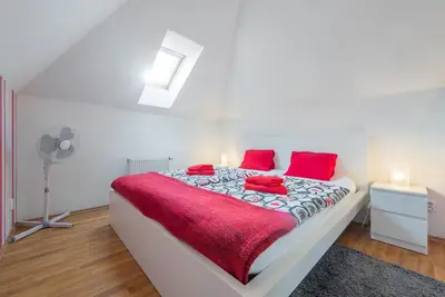 a white bedroom with a large bed with red pillows at Large Duplex Apartment with a Sunny Terrace in Prague