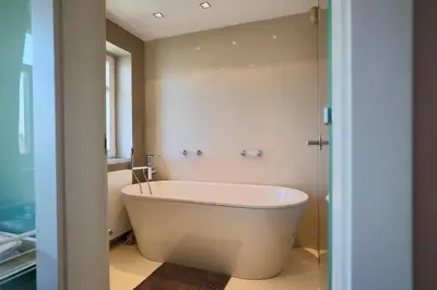 a white bath tub in a bathroom with a shower at Luxury Prague Penthouse with Heated Floors, Castle Views & Rooftop Terrace in Prague