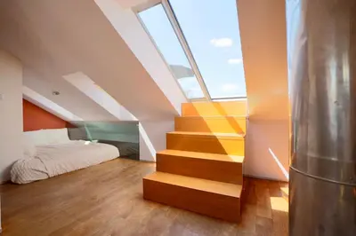 a bedroom with a staircase and a bed with a window at Luxury Prague Penthouse with Heated Floors, Castle Views & Rooftop Terrace in Prague