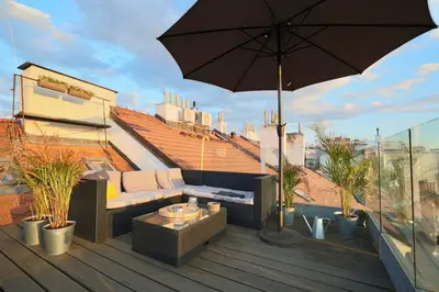 a patio with a couch and an umbrella on a roof at Luxury Prague Penthouse with Heated Floors, Castle Views & Rooftop Terrace in Prague
