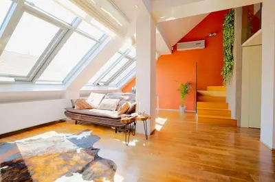 an attic living room with orange walls and a couch at Luxury Prague Penthouse with Heated Floors, Castle Views & Rooftop Terrace in Prague