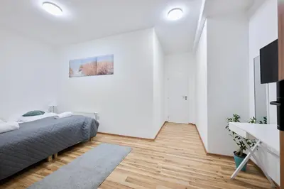 a white bedroom with a bed and a television at MIRA apartments in Prague