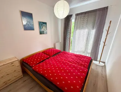 a red bed in a room with a window at Byt u letiště v Praze in Tuchoměřice