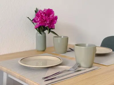 a table with plates and a vase with a pink flower at Cheerful apartment in the heart of Prague in Prague