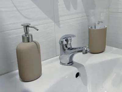 a bathroom sink with a soap dispenser and a faucet at Cheerful apartment in the heart of Prague in Prague