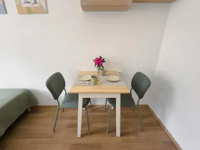 a table with three chairs and a vase of flowers on it at Cheerful apartment in the heart of Prague in Prague