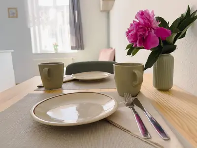 a table with a plate and a vase with pink flowers at Cheerful apartment in the heart of Prague in Prague