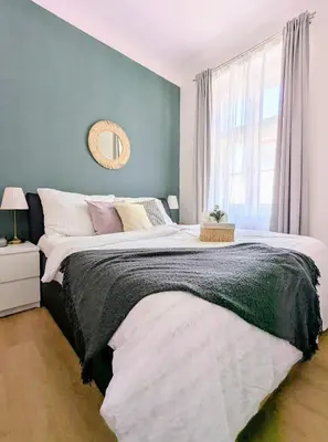 a bedroom with a large bed with a blue wall at New Town 2 BDR, free coffee in Prague