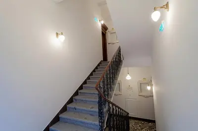 a white bedroom with a bed and a staircase at VINOHRADSKY DUM Residence in Prague