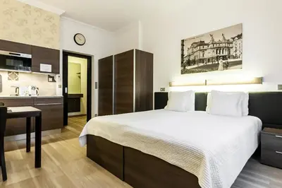 a bedroom with a bed and a desk and a kitchen at VINOHRADSKY DUM Residence in Prague