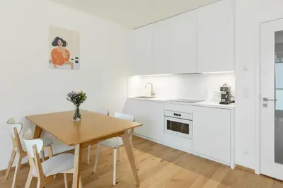 a kitchen with a wooden table and white cabinets at Contemporary apartment with garage parking in Prague