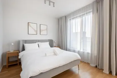 a white bedroom with a large bed and a window at Cool All-in Apartment Prague in Prague