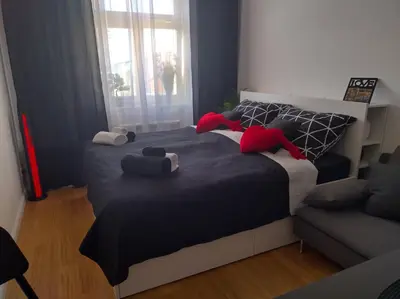 a bedroom with a bed with red pillows and a couch at Комфортная, уютная,романтичная in Prague