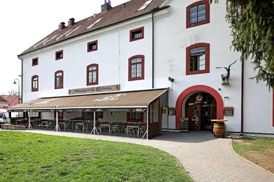 a white building with tables and chairs in front of it at Hotel u Ledu in Velké Popovice