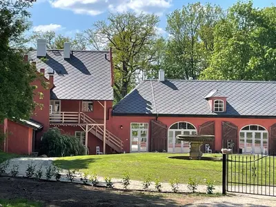 a large red house with a fenced in yard at Zámecká Stodola - Červený Hrádek u Sedlčan in Sedlčany