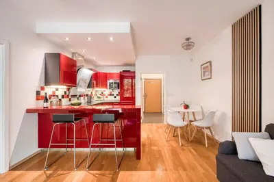 a kitchen with red cabinets and a table and chairs at Apartment with garden in Prague 6 in Prague