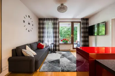 a living room with a couch and a clock on the wall at Apartment with garden in Prague 6 in Prague