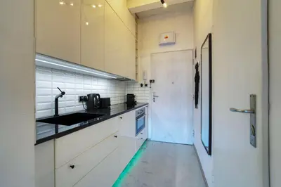a kitchen with white cabinets and a sink and a door at Modern Industry Studio in Prague
