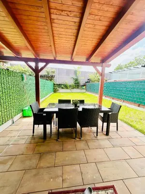 a patio with a table and chairs under a wooden roof at Villa many separate rooms with Free Parking Praha 4 libuš in Prague