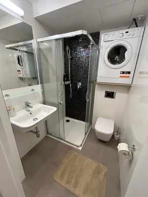 a bathroom with a shower sink and a washing machine at Pistachio Apartment National Museum View in Prague