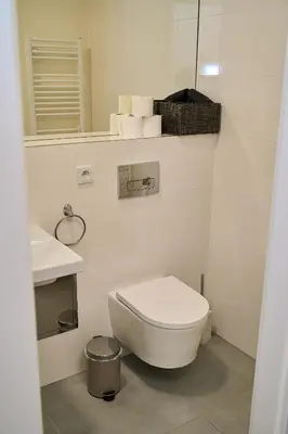 a white bathroom with a toilet and a sink at Čenětická Apartment in Prague
