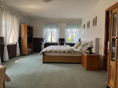 a bedroom with a large bed and two windows at Luxusní chalupa Kokořínsko