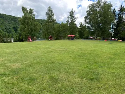 a large grass field with a playground in the distance at Solo tábořiště, kemp u vody, Nová Živohošť in Křečovice