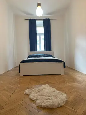 a bedroom with a bed and a rug on a wooden floor at Spacious place on Metro station Andel in Prague