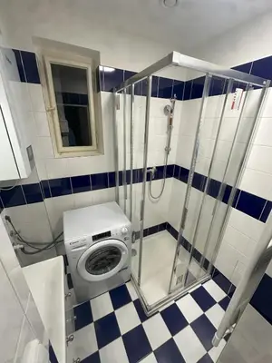 a bathroom with a shower with a washing machine at Spacious place on Metro station Andel in Prague