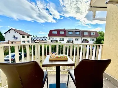 a balcony with a table and two chairs and a cake at Royal Villas in Prague