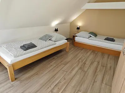 two beds in a room with wooden floors at Apartmány Zámecká in Roudnice nad Labem