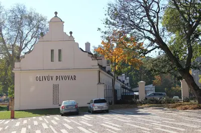 two cars parked in a parking lot in front of a building at Olivův Pivovar in Dolní Břežany