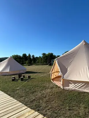 two tents in a field next to a wooden deck at Čerčanská Koupadla - glampingové stany in Benešov