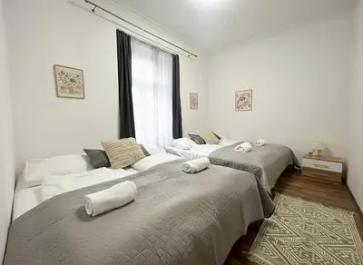 two beds in a white room with a window at City & River Apartment in Prague