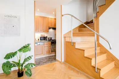 a staircase in a kitchen with wooden cabinets and a potted plant at Prague Days - Maisonette Retreat with Terrace, AC and TV Tower View in Prague