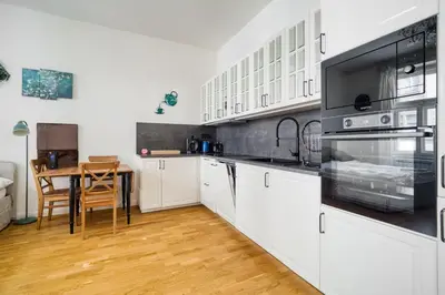 a kitchen with white cabinets and a wooden table at Cozy Nest by Karlín Square in Prague