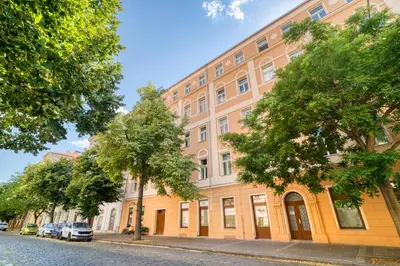 an orange building with trees in front of a street at Cozy Nest by Karlín Square in Prague