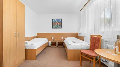 a room with two beds and a desk and a table at Hotel Samechov - konferenční hotel in Samechov