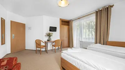 a hotel room with two beds and a table at Hotel Samechov - konferenční hotel in Samechov