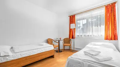 a bedroom with two beds and a table and a window at Hotel Samechov - konferenční hotel in Samechov