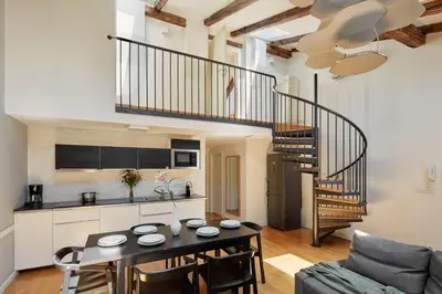 a living room with a table and a spiral staircase at Prague Days - Maisonette with AC and 2 Bathrooms in New Town in Prague