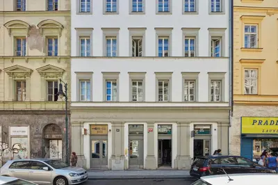 a large white building with cars parked in front of it at Prague Days - Maisonette with AC and 2 Bathrooms in New Town in Prague