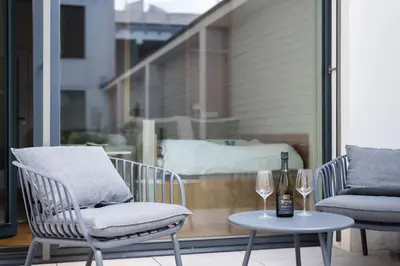 two chairs and a table with wine glasses on a balcony at Olive Garden Apartment with Garage in Prague