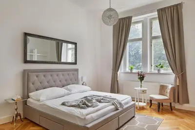 a bedroom with a bed and a mirror and a chair at Prague Days - Deluxe Apartment with Balcony overlooking gardens in Lesser Town in Prague