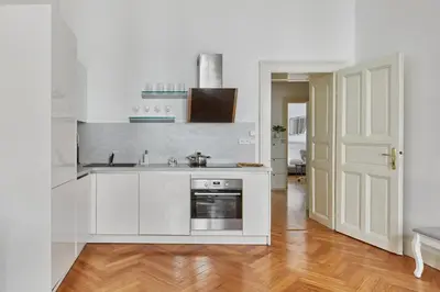 a white kitchen with a sink and a stove at Prague Days - Deluxe Apartment with Balcony overlooking gardens in Lesser Town in Prague